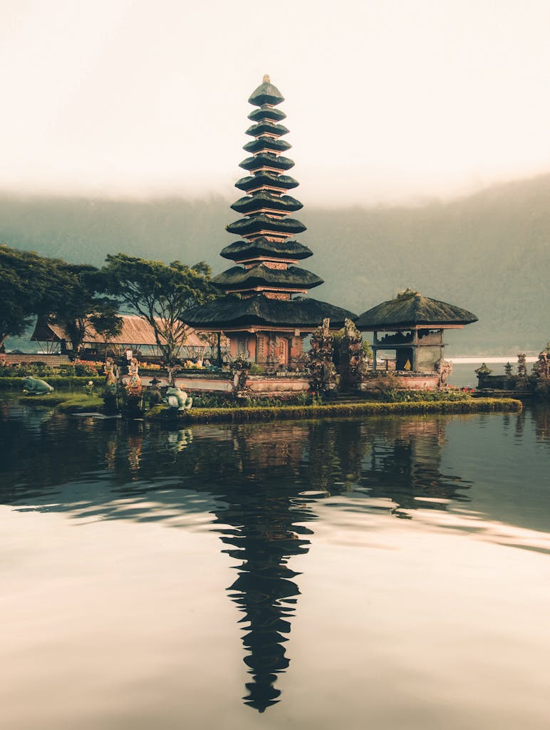 A serene view of Ulun Danu Beratan Temple with reflections on the water at sunrise, Bali, Indonesia.