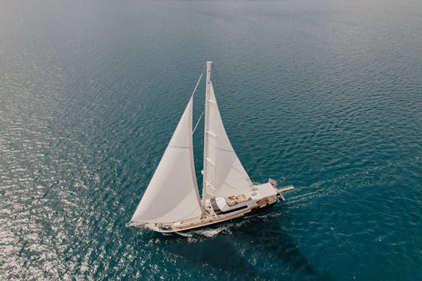 Sailing Holiday Concierge 2 A classic sailboat cuts through the pristine blue water under a clear sky.