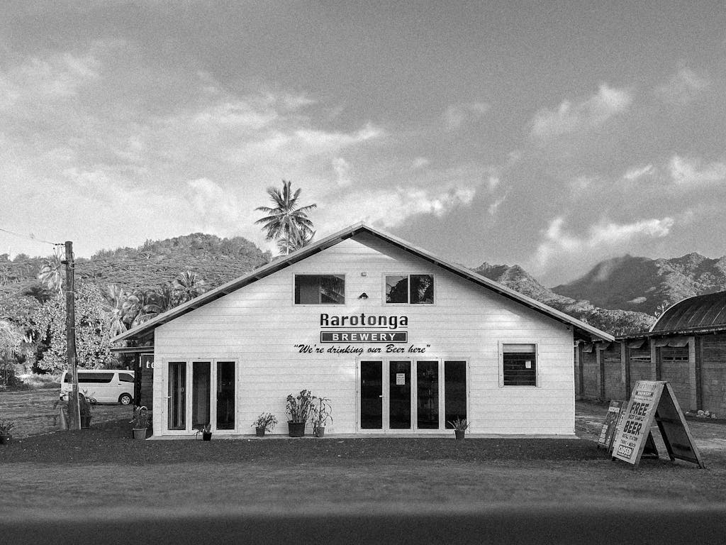 Black and white photo of Rarotonga Brewery with mountains in the background.