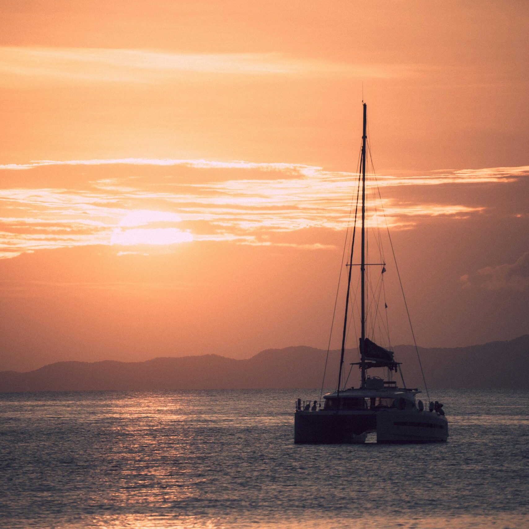 A stunning silhouette of a sailboat cruising at sunset in Ao Nang, Thailand's serene waters.
