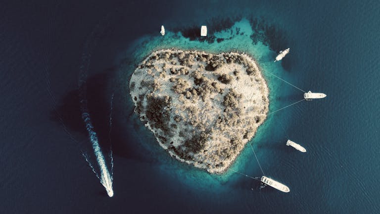 Stunning aerial shot of a heart-shaped island surrounded by boats in Göcek, Türkiye.