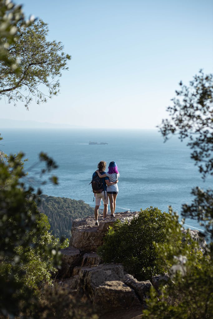 A couple stands on a cliff in Istanbul, enjoying a scenic ocean view.