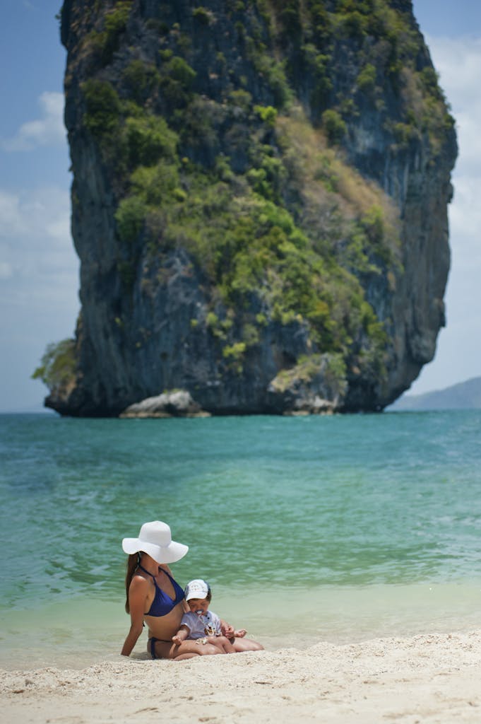 A mother and child relaxing on Ao Nang beach with a scenic limestone backdrop in Krabi, Thailand.