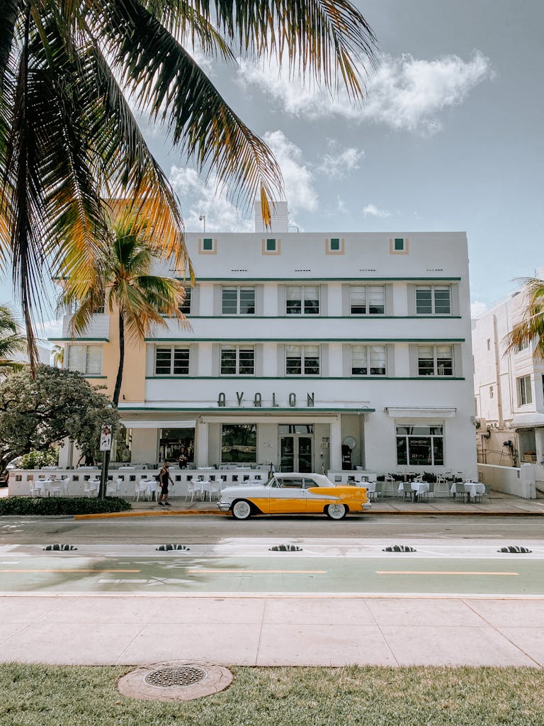 Art Deco hotel in Miami's South Beach with a classic yellow car parked in front.