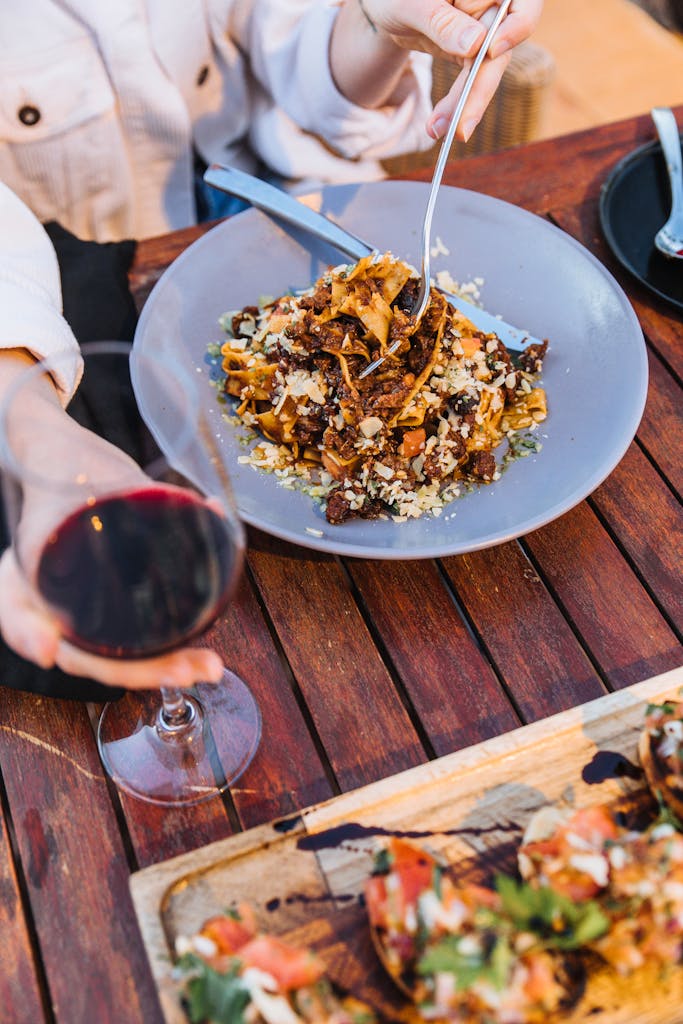 Close-up of pasta and red wine on a dining table, highlighting authentic Italian cuisine.