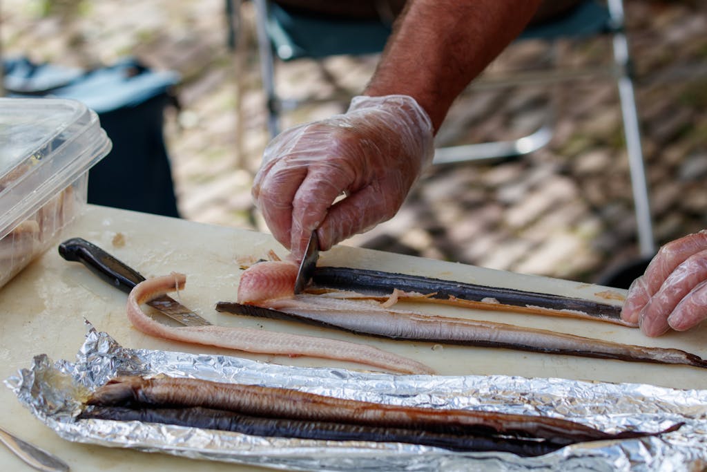 Hands preparing fish fillets outdoors, showcasing culinary skills and fresh ingredients.