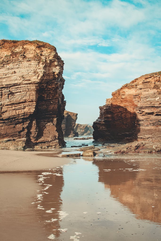 Majestic rocky cliffs at low tide revealing unique geological formations on a tranquil beach.