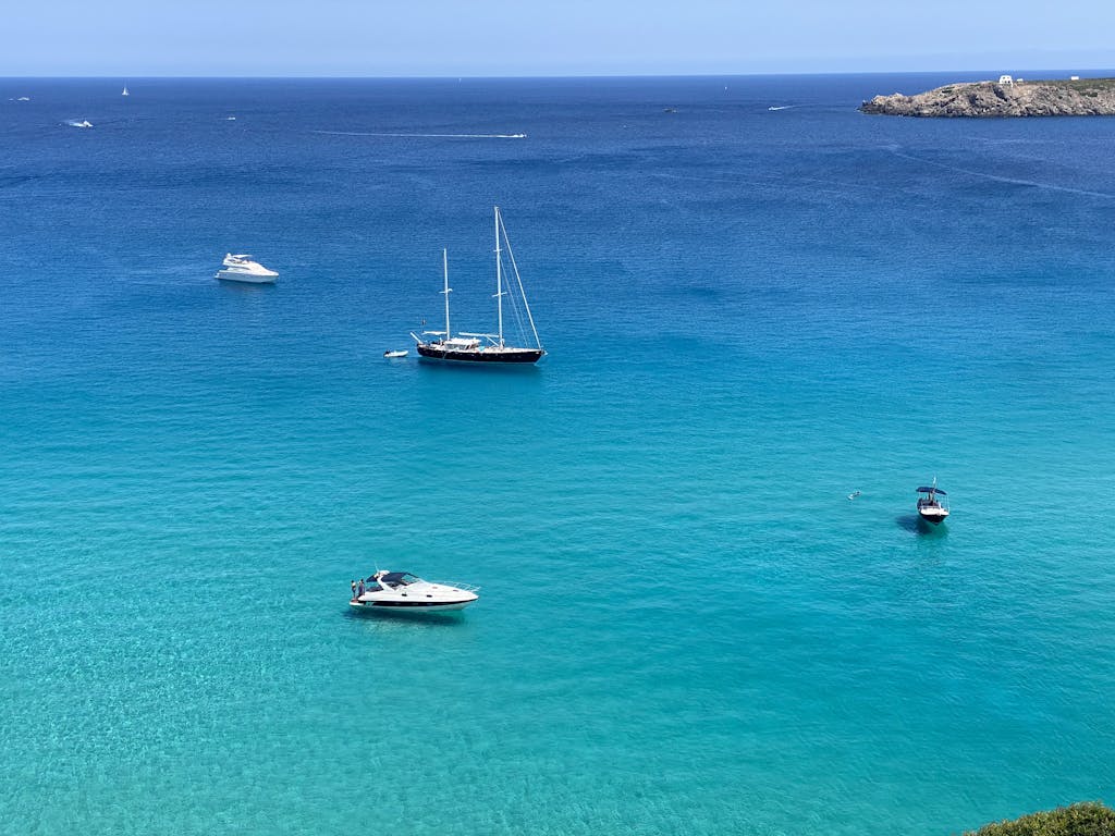 Serene view of sailboats on the turquoise waters at Ciutadella de Menorca, Spain.
