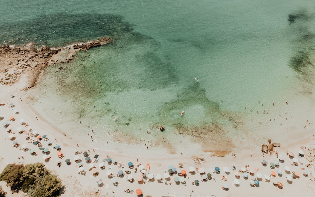 Stunning aerial shot of Monti D'arena beach, Puglia, Italy, capturing vibrant umbrellas and clear turquoise waters.