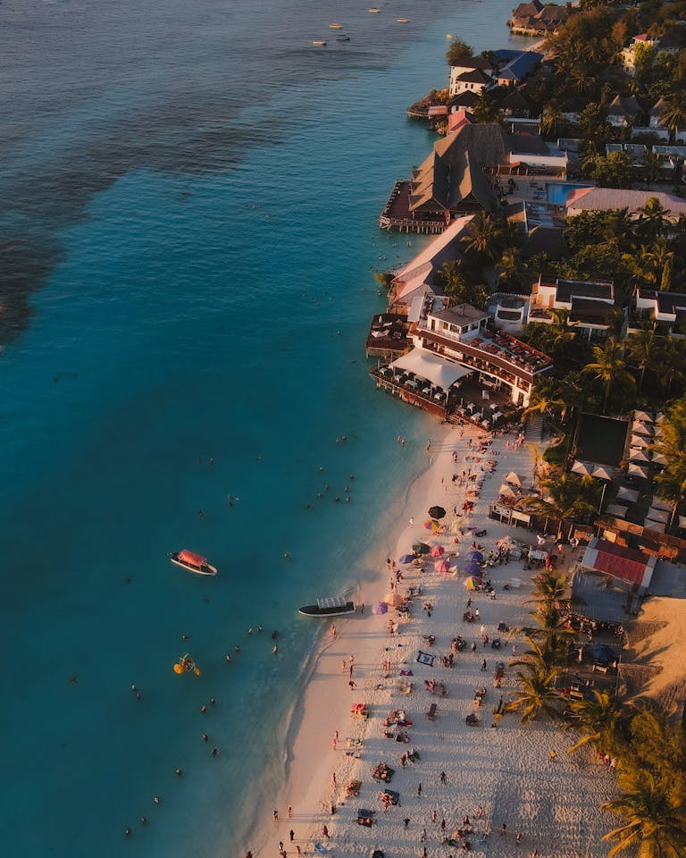 Stunning aerial shot of Nungwi Beach in Tanzania with people enjoying the shore at sunset.