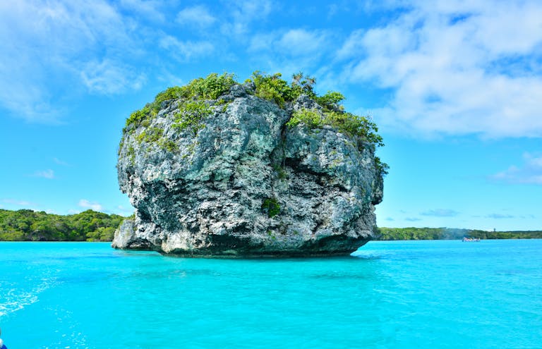 Vibrant turquoise waters and lush rock formations in Nouméa, New Caledonia.
