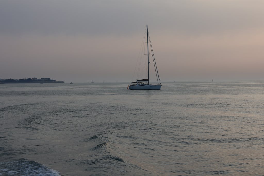 A peaceful sailboat drifts through the calm waters of Cádiz at sunset, showcasing the beauty of Andalucía, Spain.