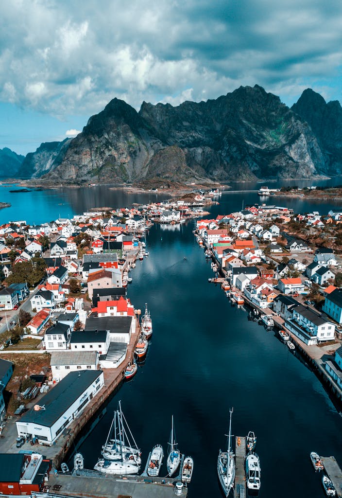 Breathtaking aerial view of a quaint village in Lofoten, Norway, surrounded by majestic mountains and calm seas.